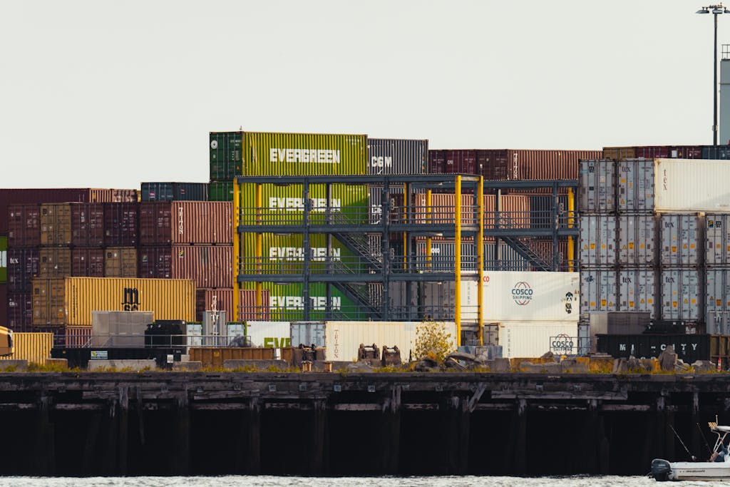 Colorful shipping containers stacked at a busy seaside dock.